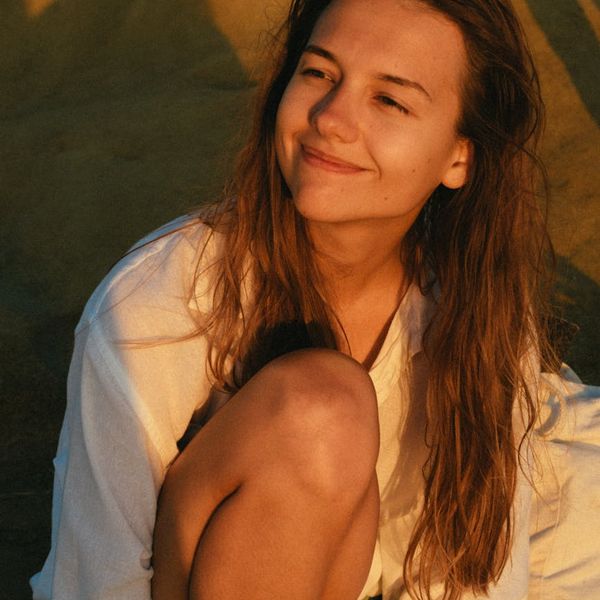 Smiling person sitting peacefully outdoors after a light workout.